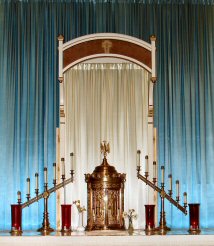 A gold
        altar with candles and a blue curtainDescription automatically
        generated